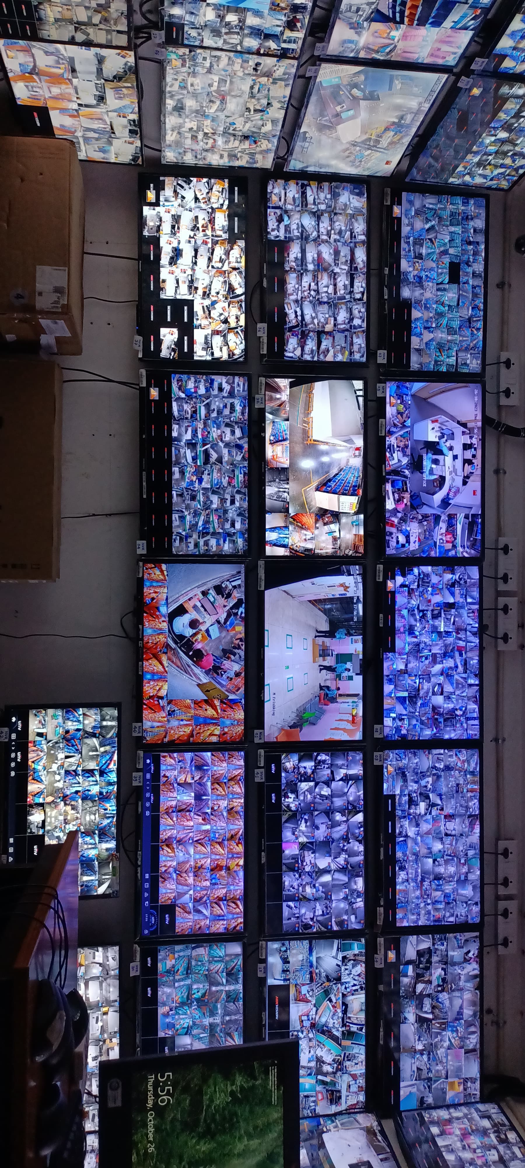 Numerous security monitors on a wall showing a grid of live CCTV surveillance footage.